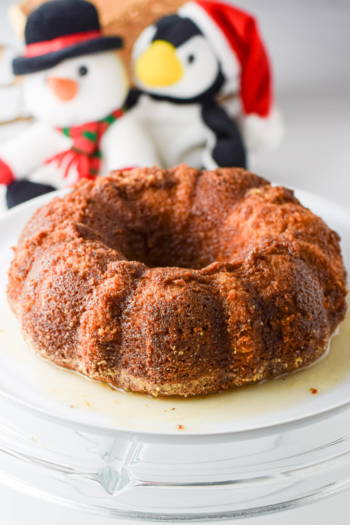 A white plate with rum soaked cake on it with stuffed animals in back