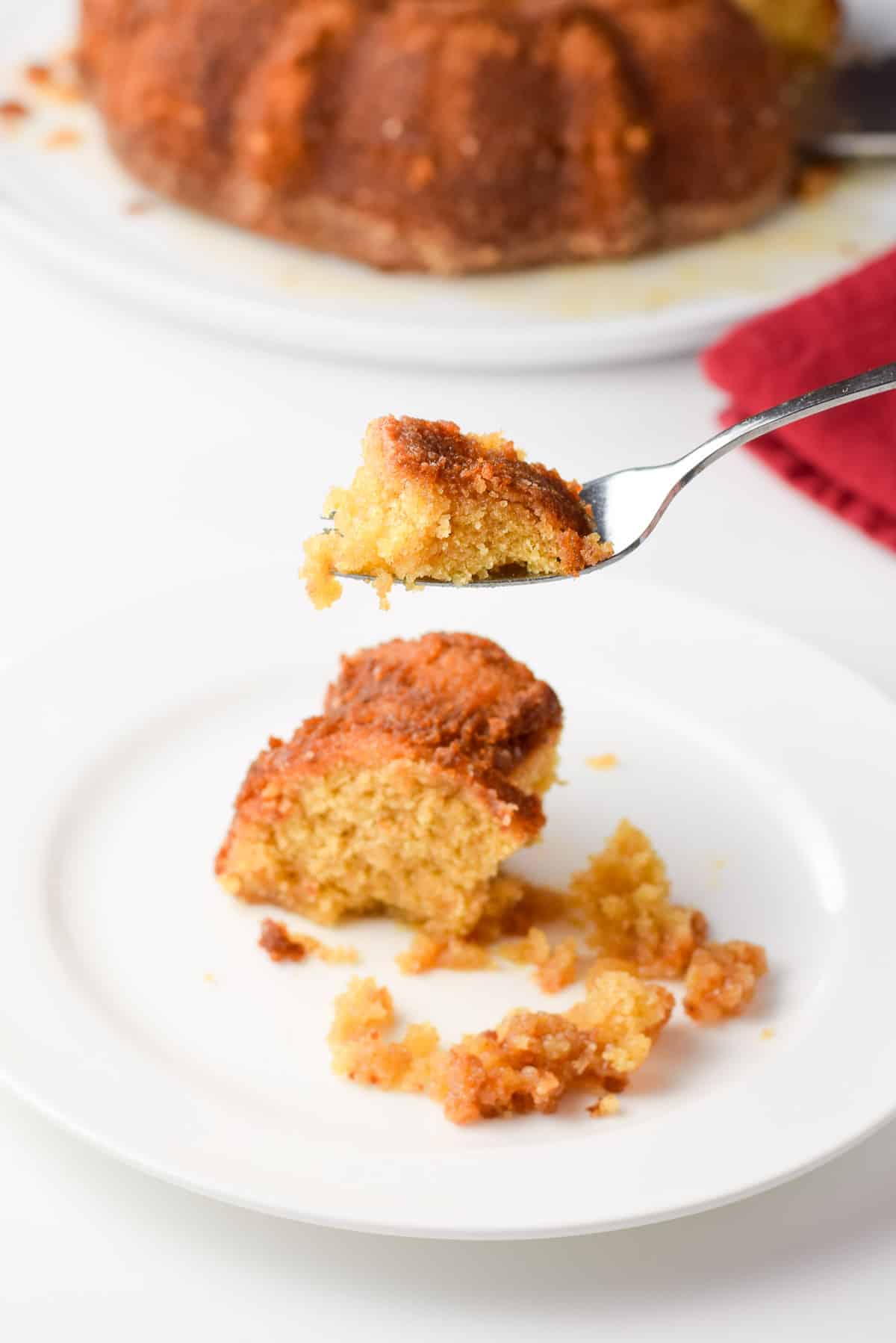 A fork with the cake on it held over the plate of the cake