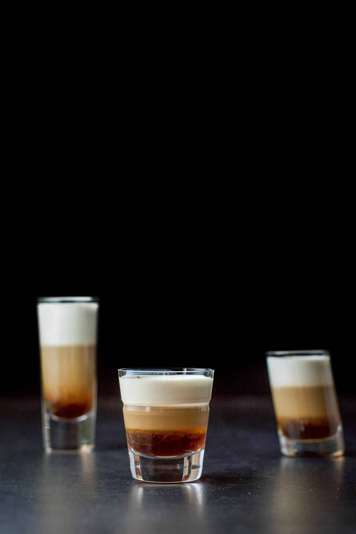 Three shot glasses filled with the tootsie roll shot with the beveled glass in front