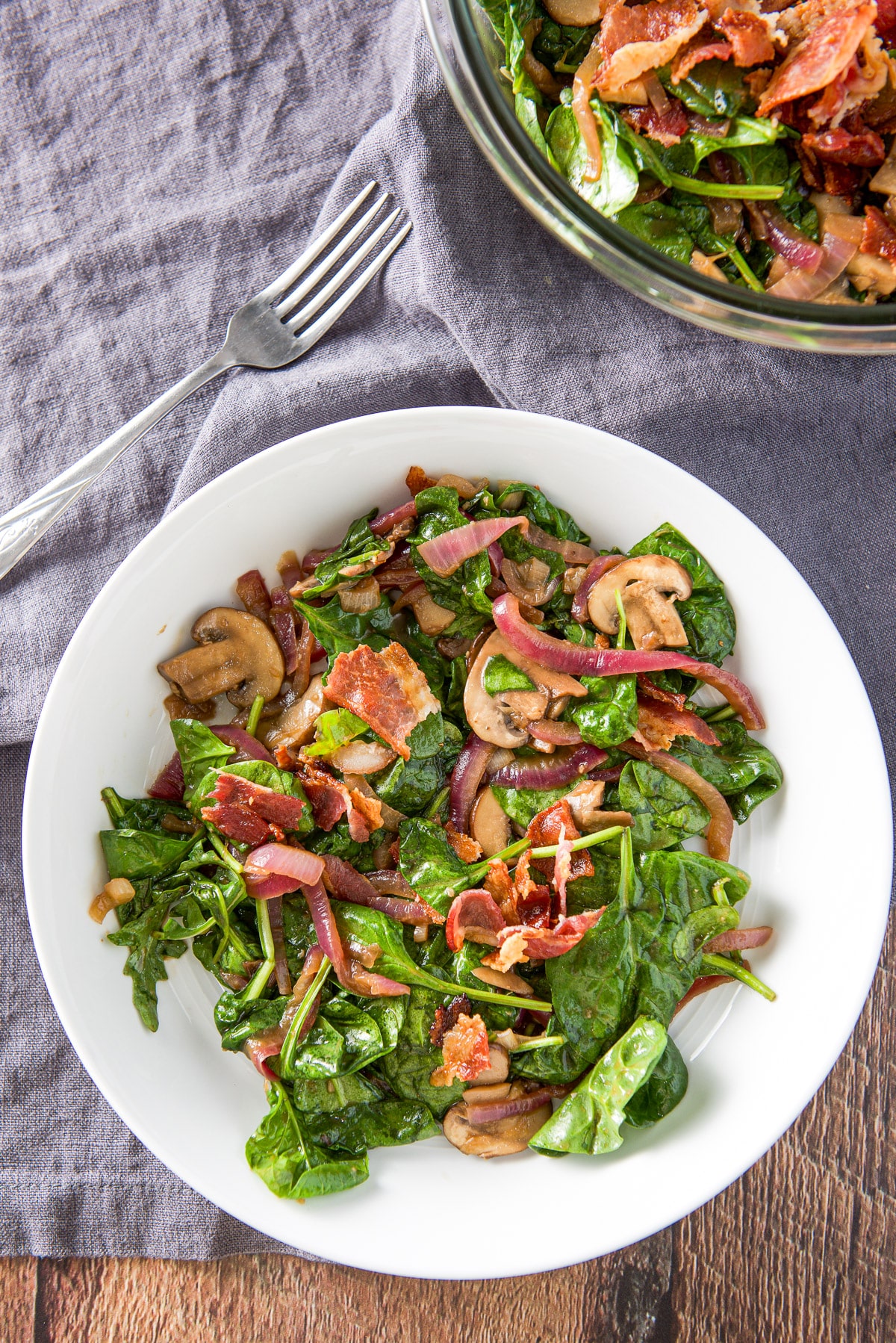 Overhead view of the white bowl of the salad and fork and the glass bowl with the rest of it.