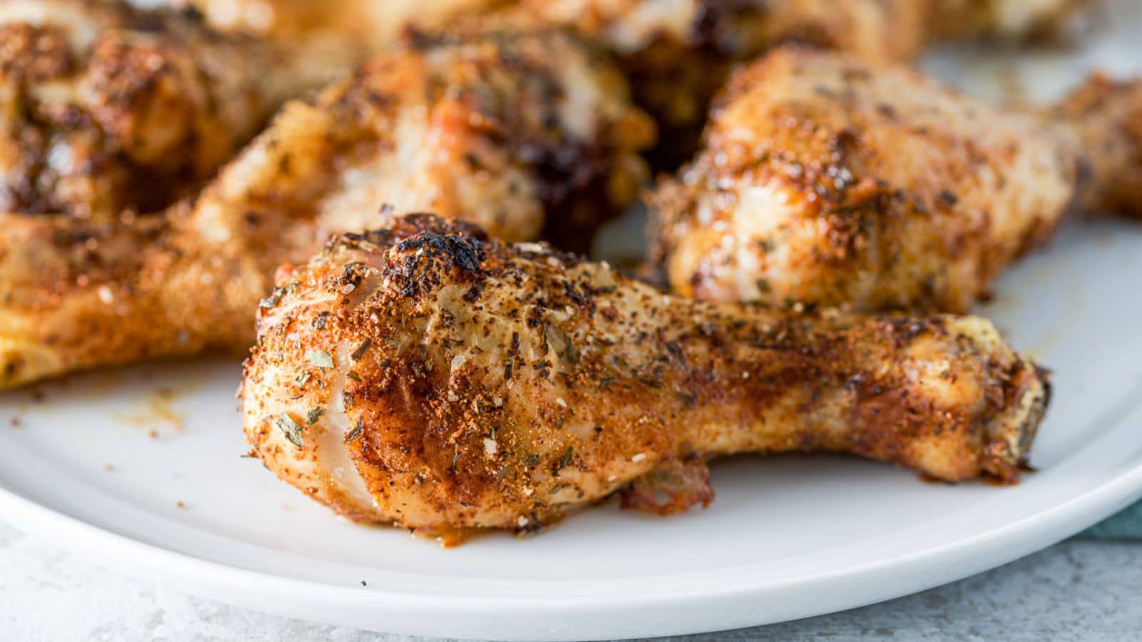 A white plate with drumsticks on it with nice crispy skin