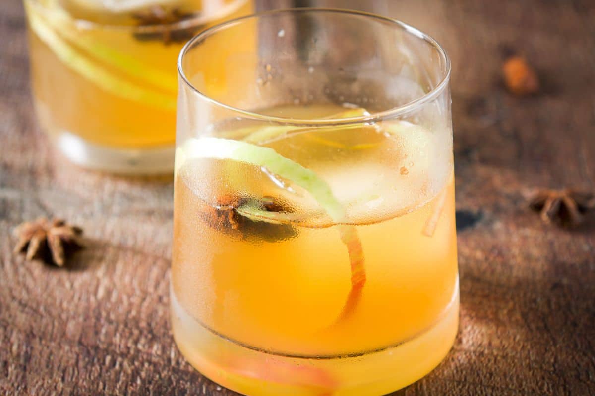 two glasses with the apple cocktail with apple peels and star anise