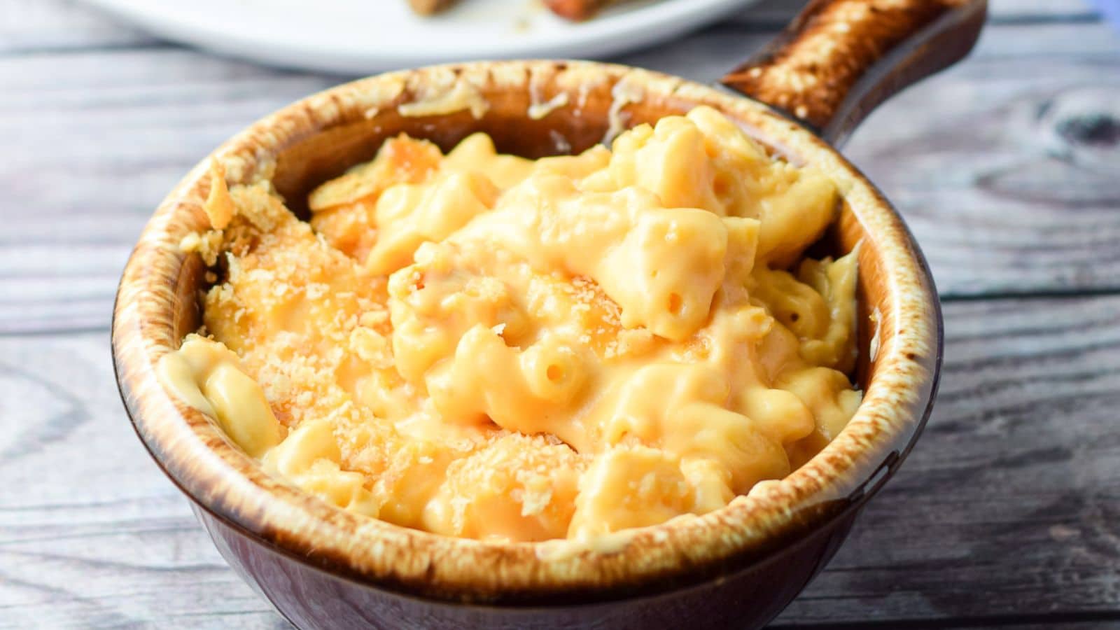 A crock filled with mac and cheese with cracker crumbs on top
