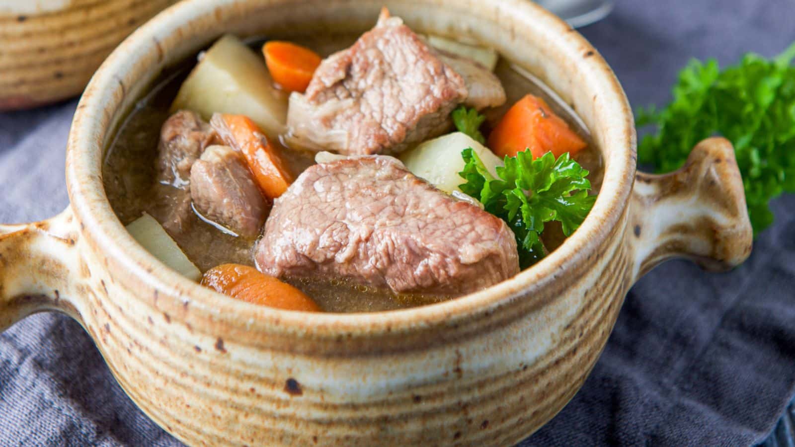 Lamb stew in a crock with parsley as garnish