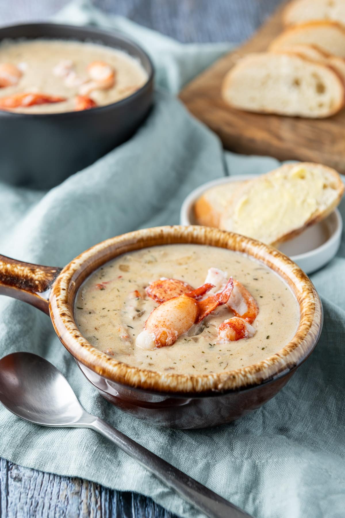 Two bowls of bisque on a napkin along with a spoon, and bread