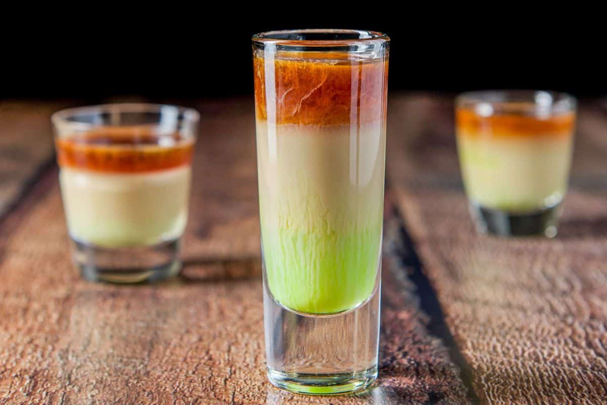 three shot classes layered with a green, beige and brown liquor