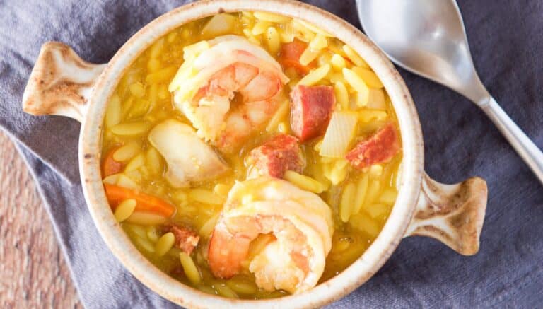 overhead view of the shrimp soup in a crock with a spoon on a napkin
