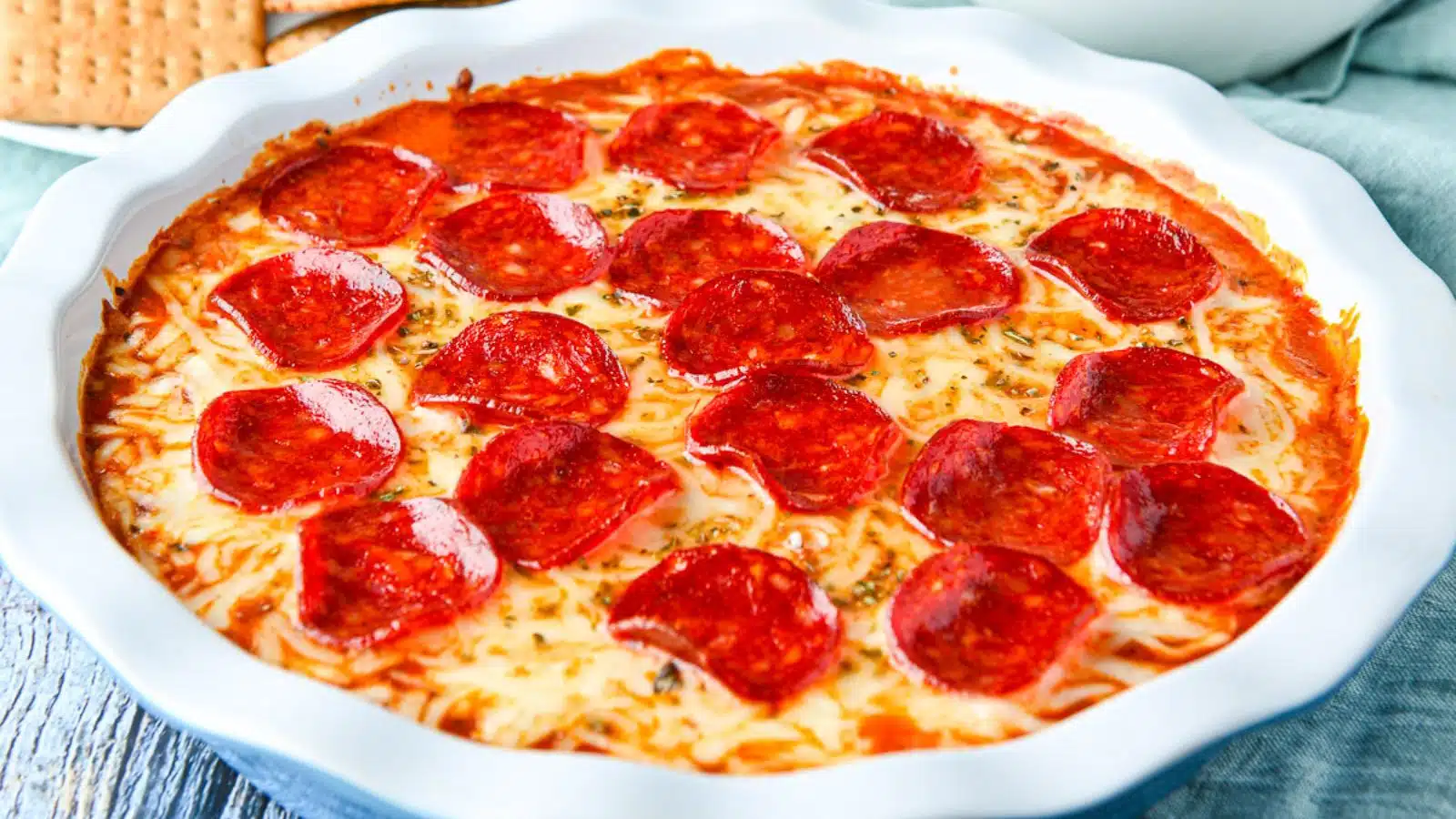 a blue pie plate with a cheesy dip with pepperoni on top