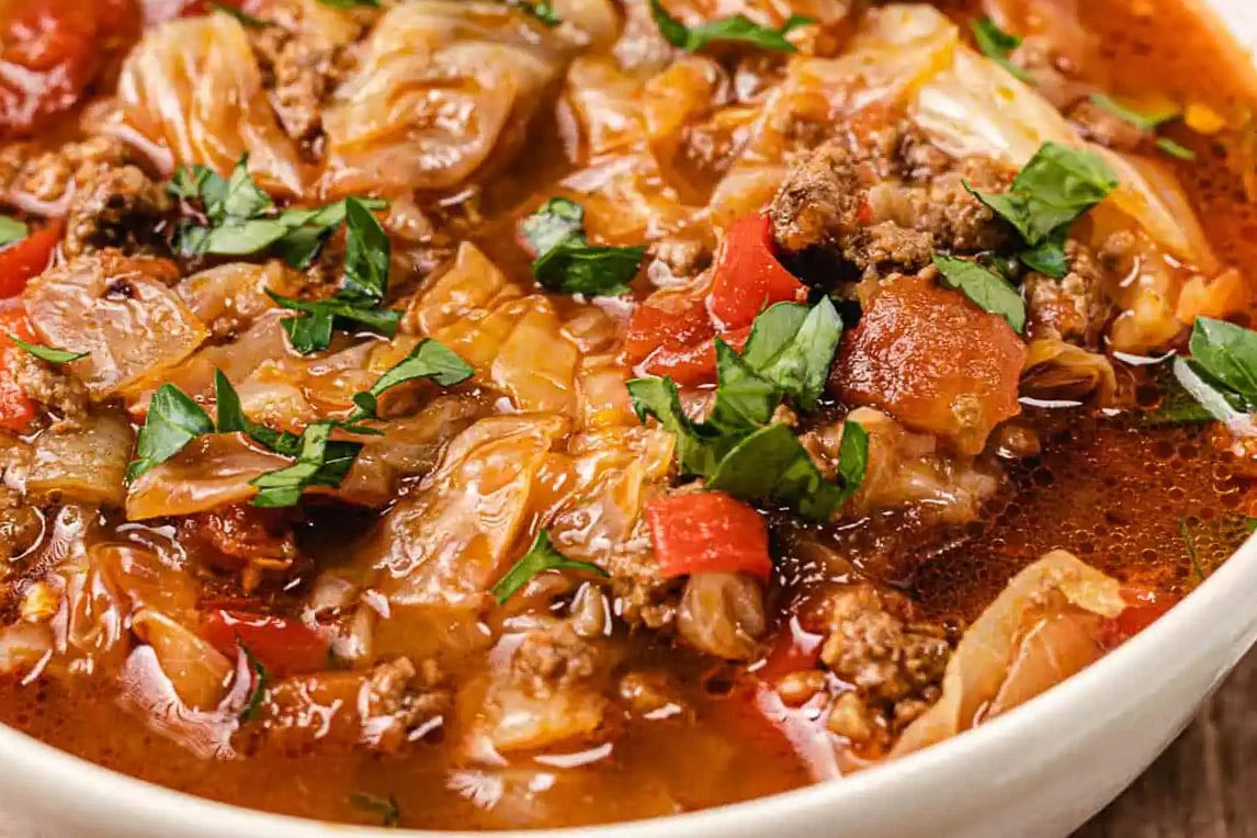 A white bowl with colorful cabbage soup in it