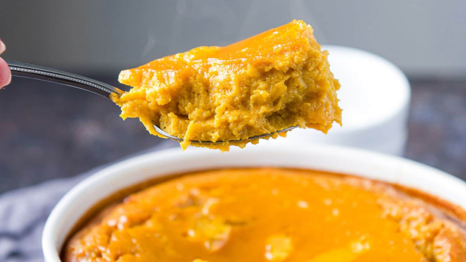 A fork with some squash on it held over the bowl of it