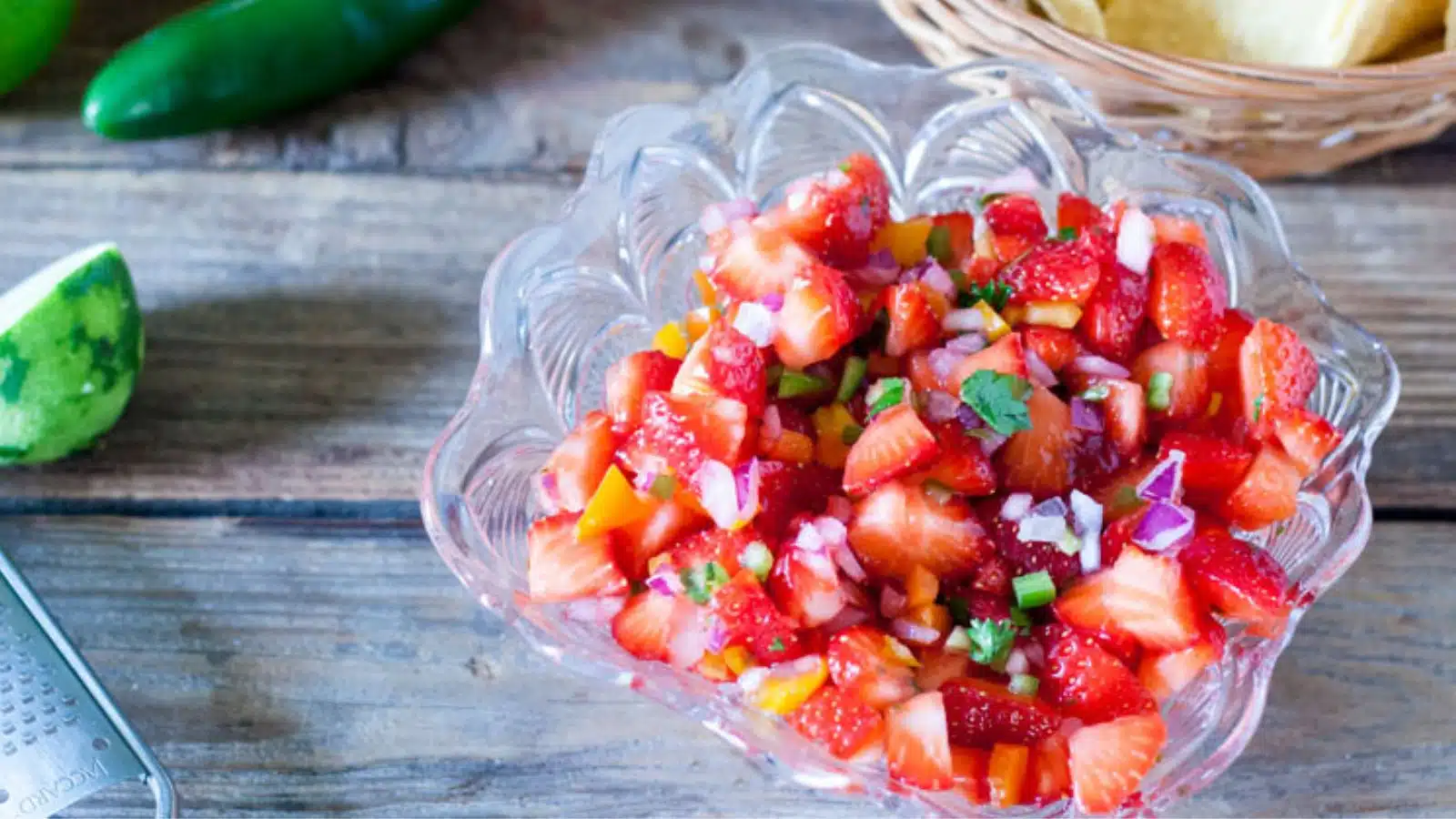strawberry salsa on a table with limes, jalapenos, and chips