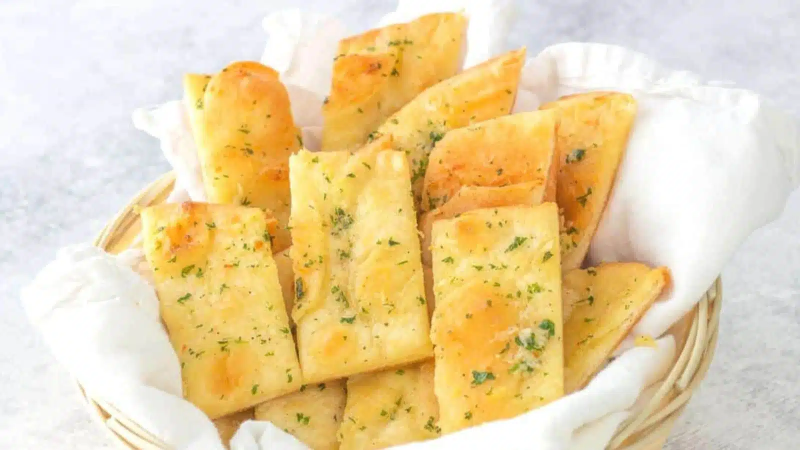 a small basket with a white napkin in it along with garlic bread