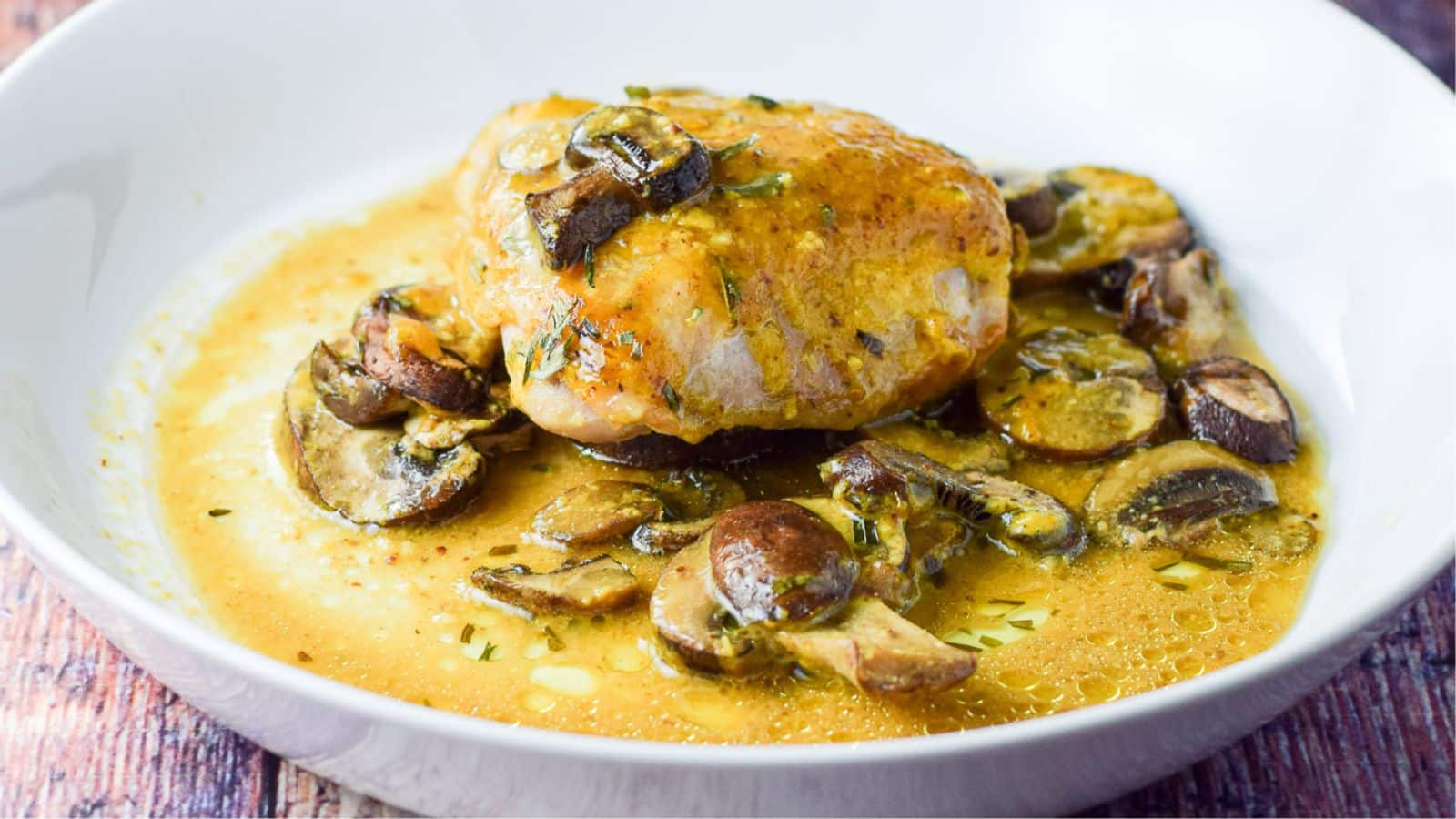 a white deep dish of chicken with mushrooms and a mustard sauce