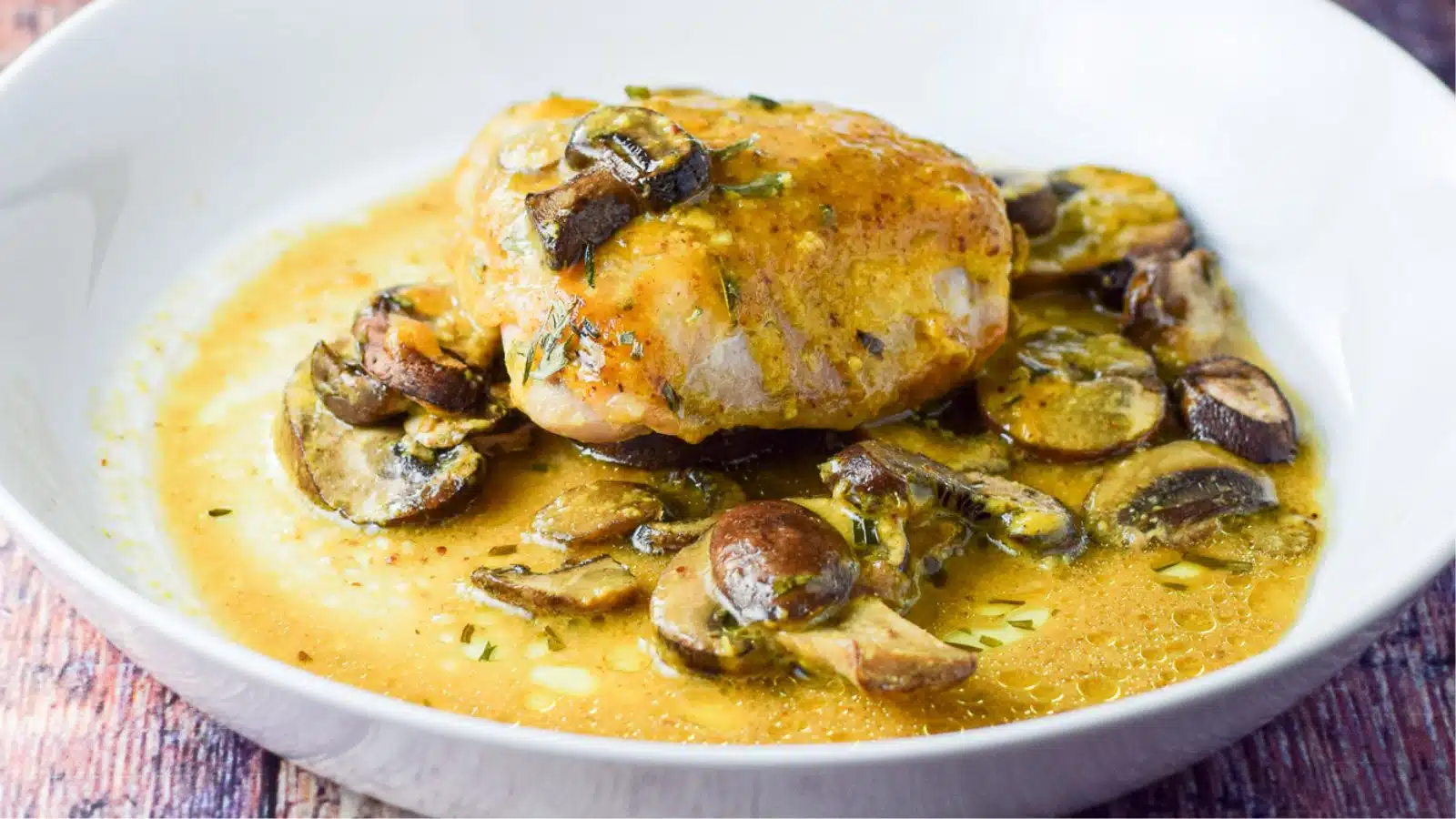 a white deep dish of chicken with mushrooms and a mustard sauce
