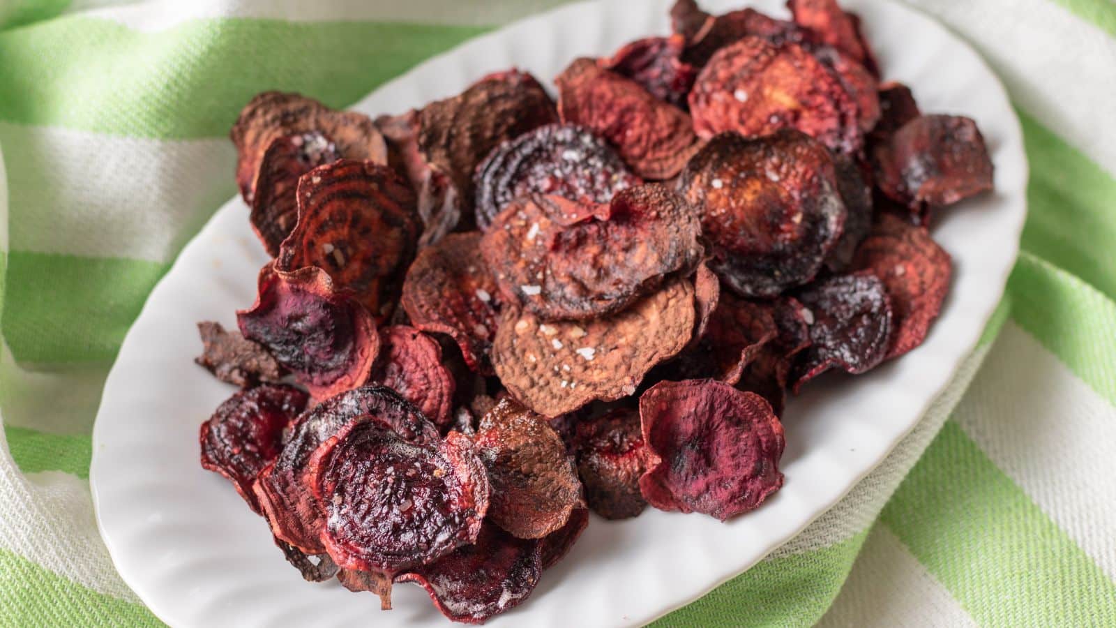 A white oval plate with beet chips on it