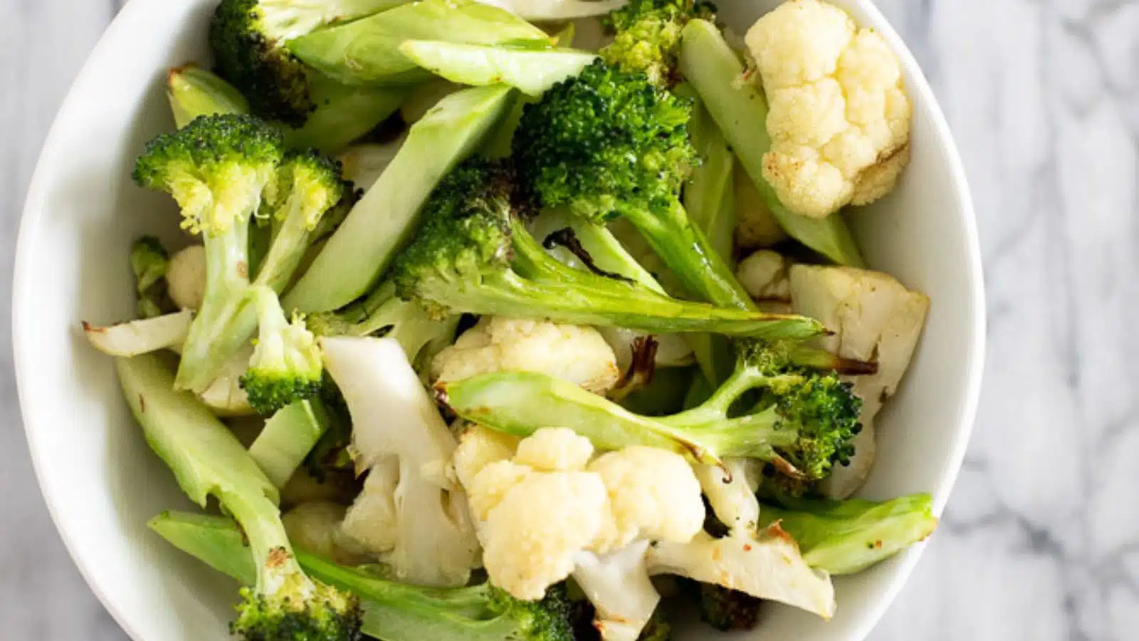 a white bowl filled with cooked cauliflower and broccoli