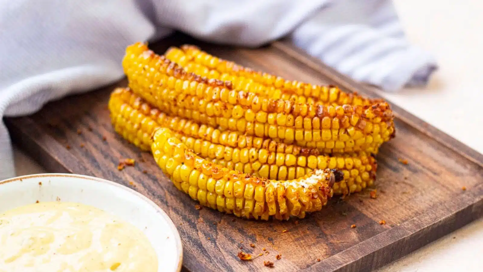 a wood board with cut ribs of corn on it and a dipping sauce