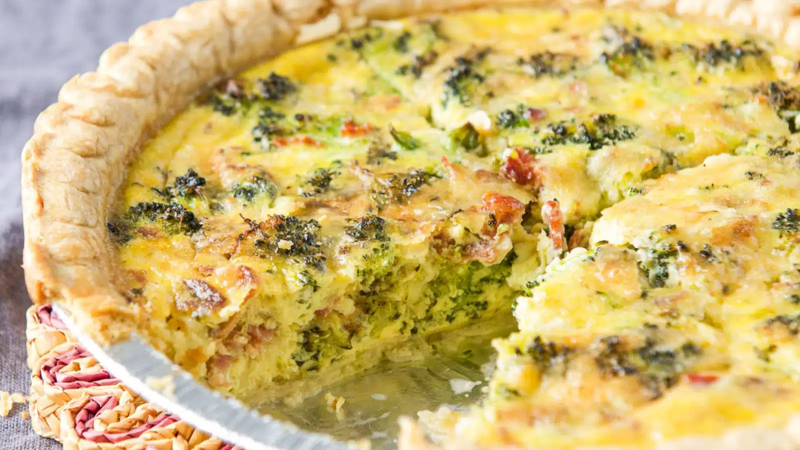 a pie plate with quiche in it with a piece cut out