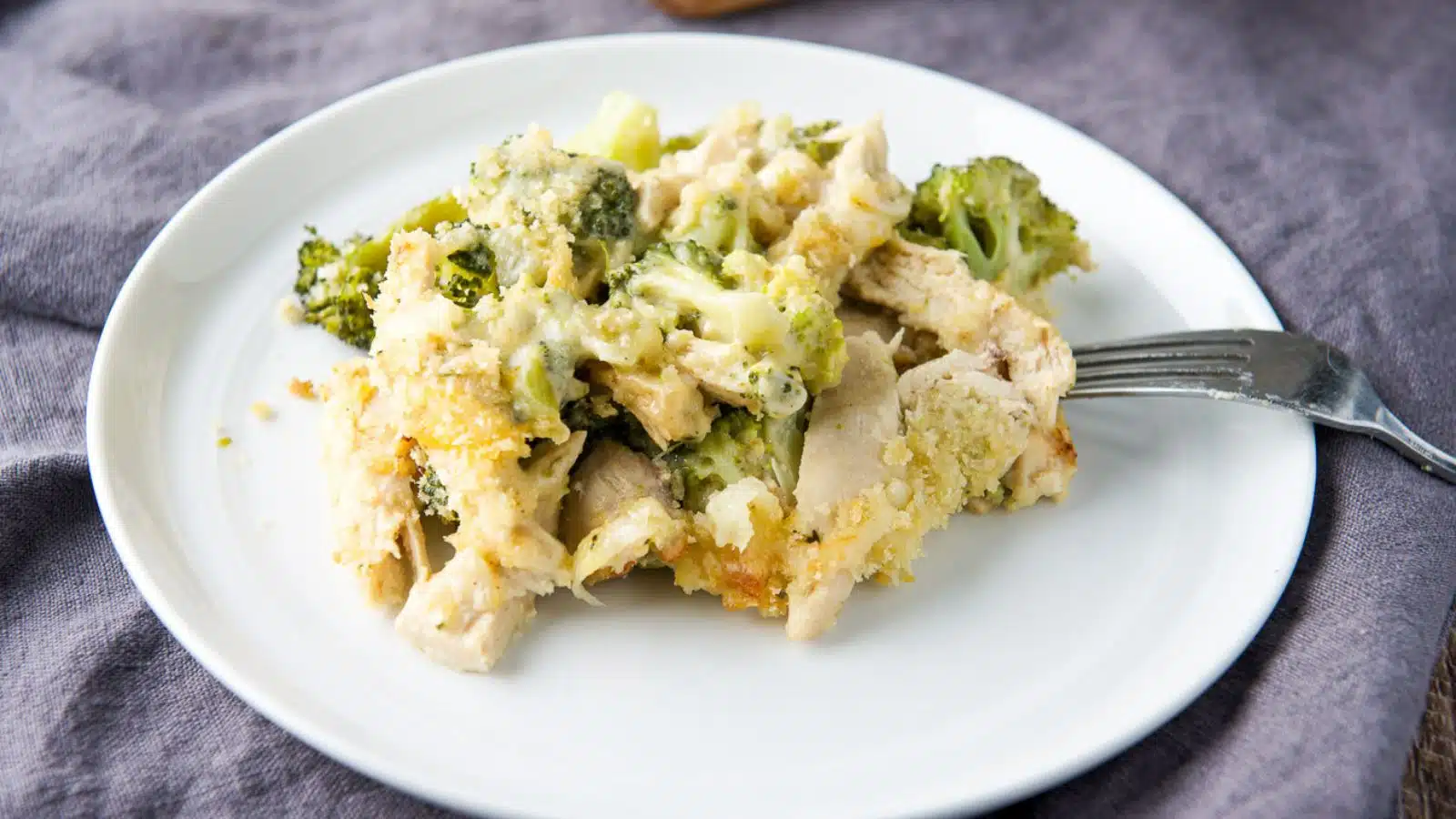 A small plate with the chicken, broccoli, and cheese ladled on it and a fork