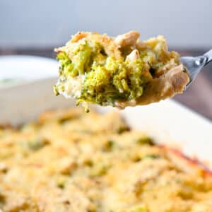 A big spoon with a scoop of chicken, broccoli, cheese, and sauce on it held over the pan - square