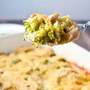 A big spoon with a scoop of chicken, broccoli, cheese, and sauce on it held over the pan - square