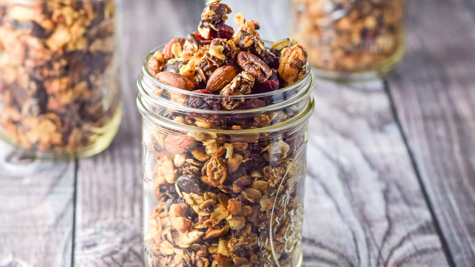 jars of cranberry granola in jars on a wood table