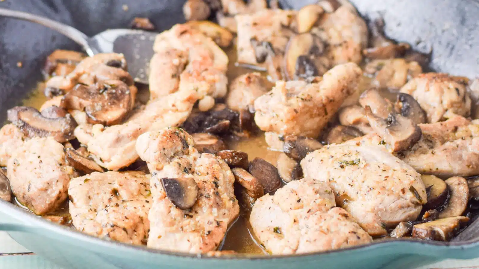 a close up view of chicken pieces in a pan with mushrooms and sauce