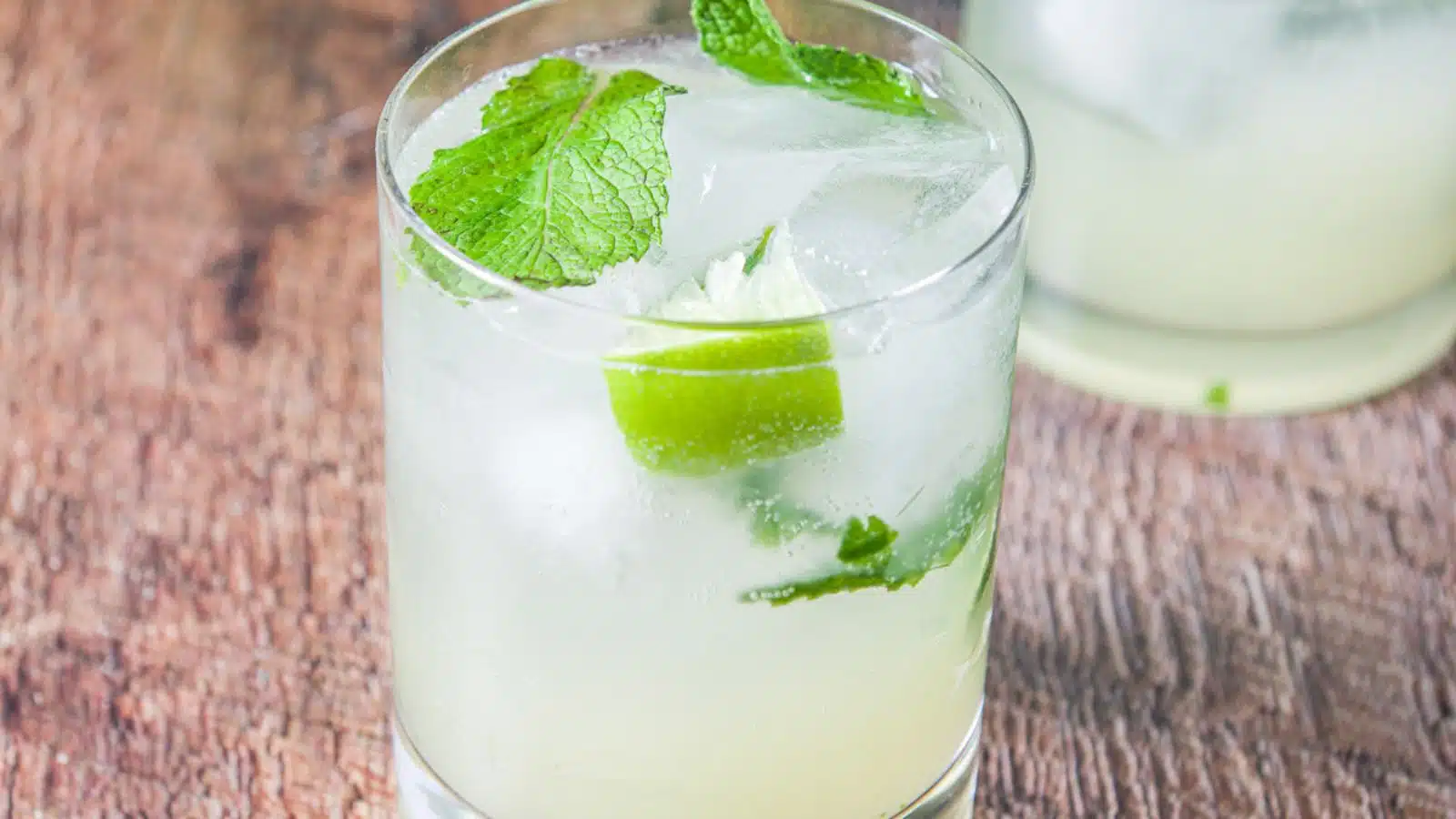 a glass filled with the mojito with lime and mint as garnish