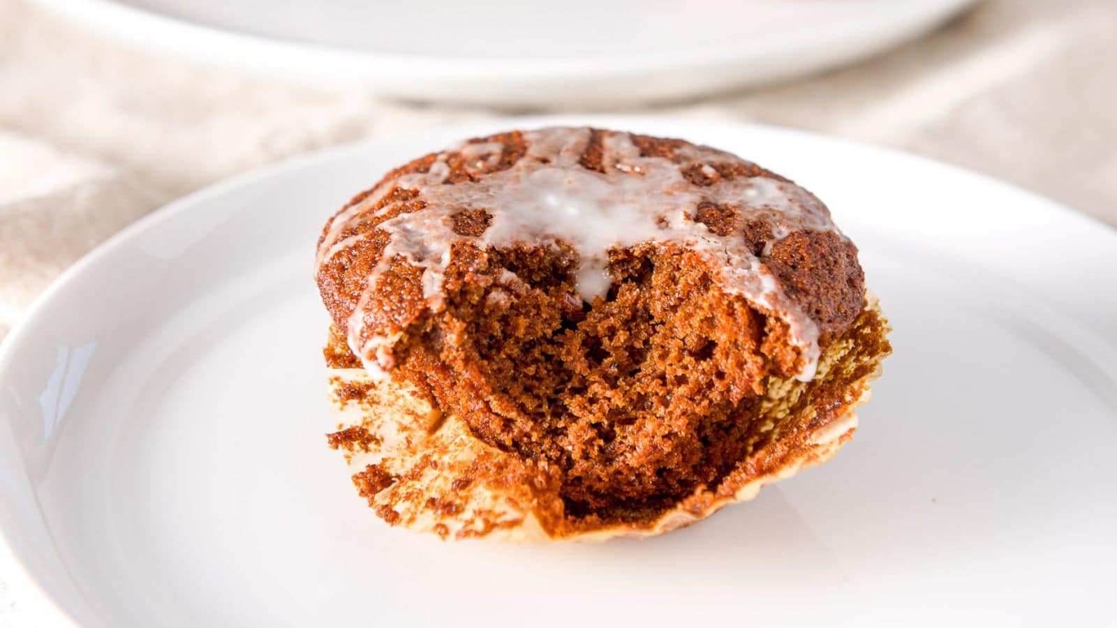 a white plate with a glazed muffin on it with a bite taken out of it