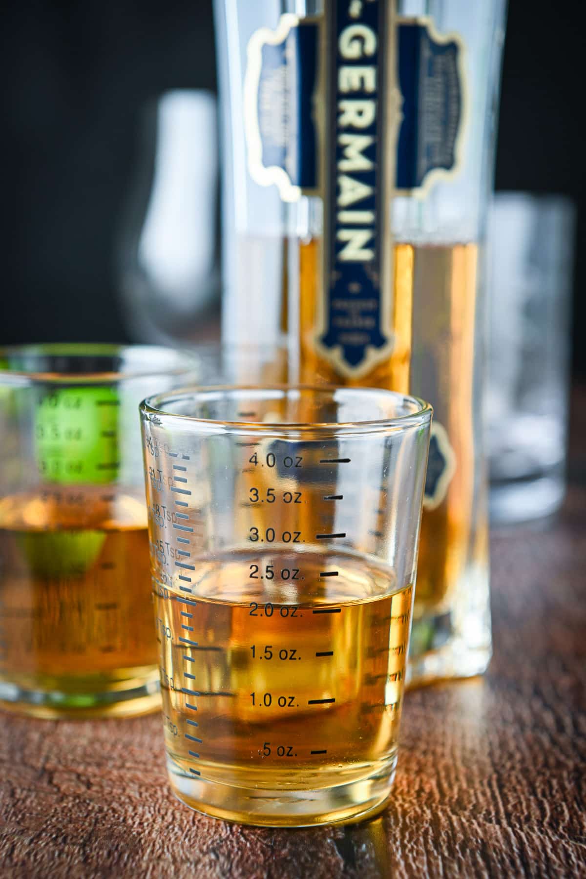 Measured out elderberry liqueur with the bottle behind it