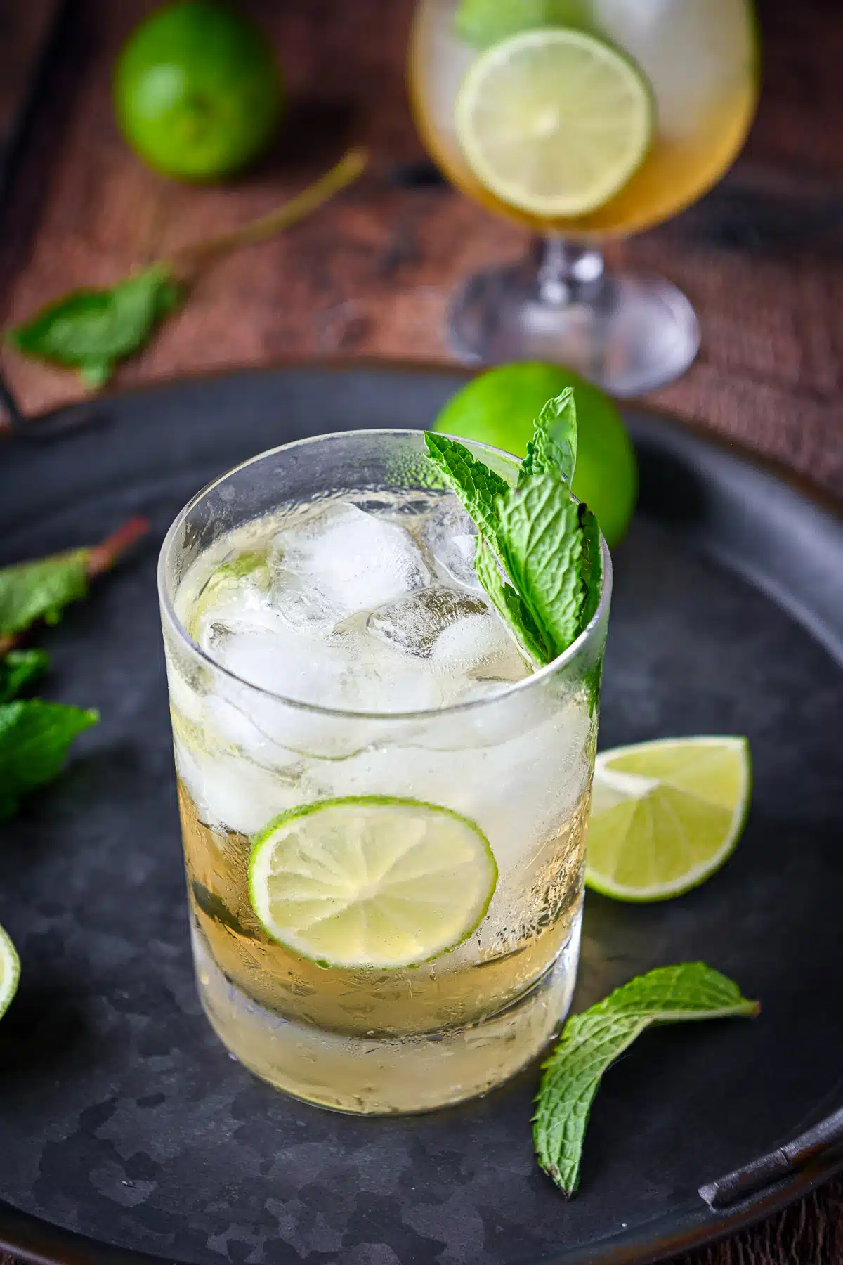Lime and mint on a tray with a glass filled with the lime cocktail