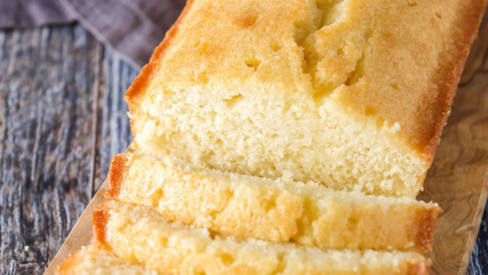 a board with a lemon bread on it showing the texture of the loaf