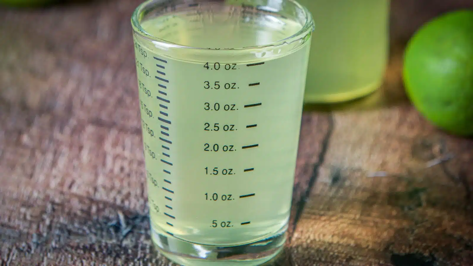 A four ounce measuring glass filled with the lime vodka
