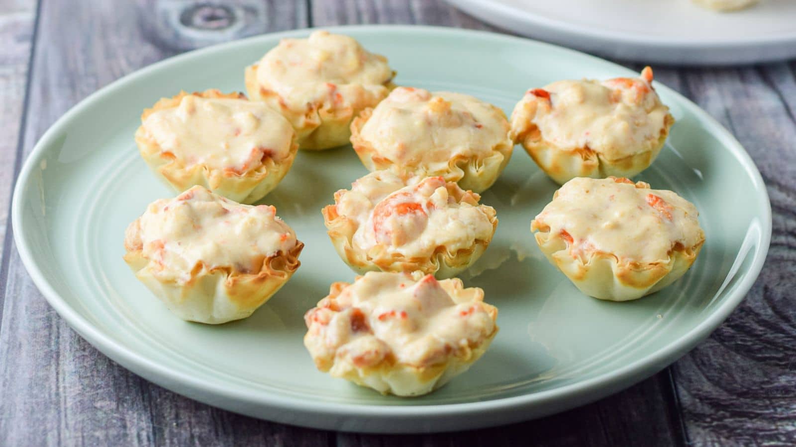 a green plate with phyllo cups filled with a lobster dip