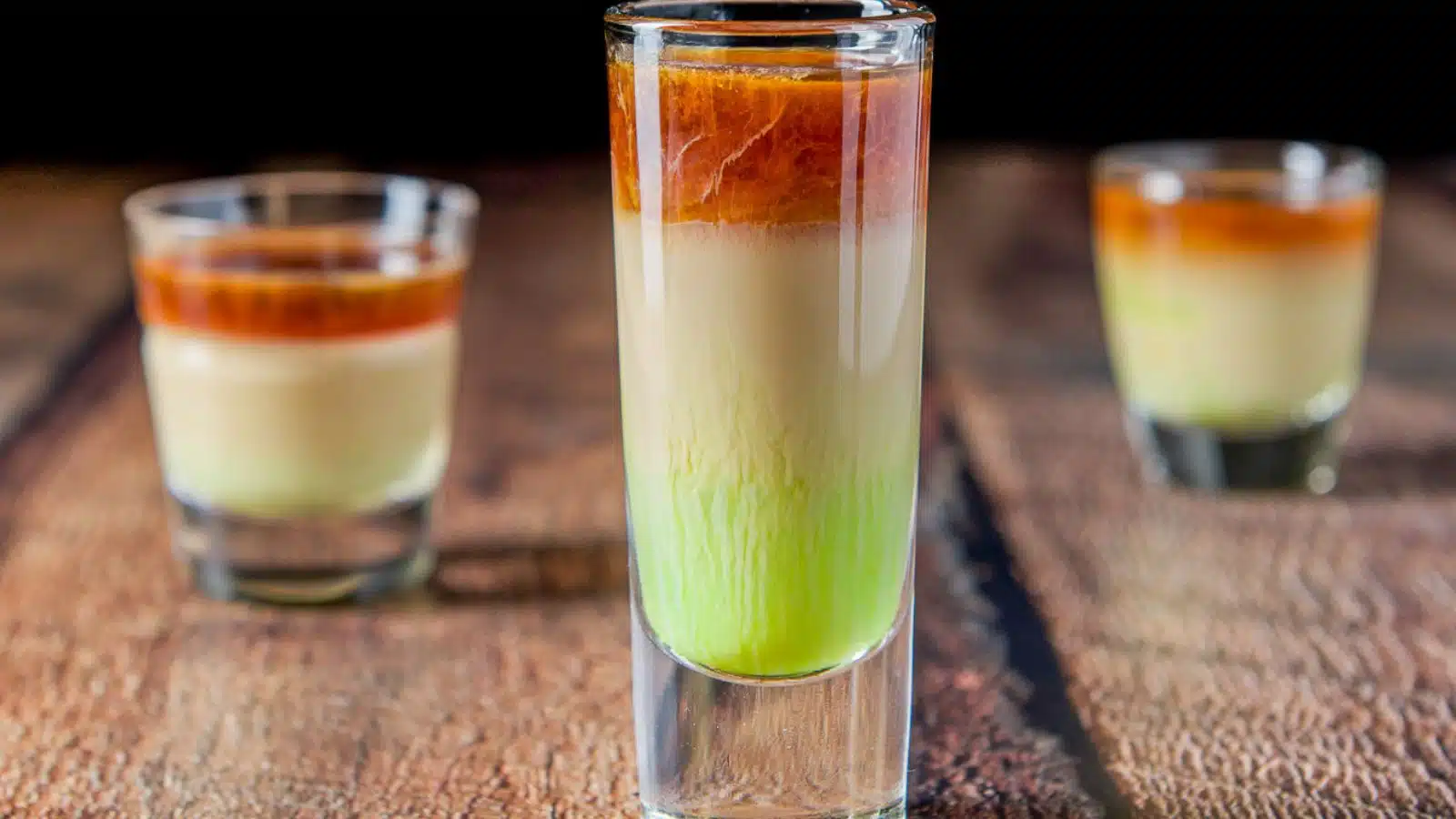 three shot classes layered with a green, beige and brown liquor