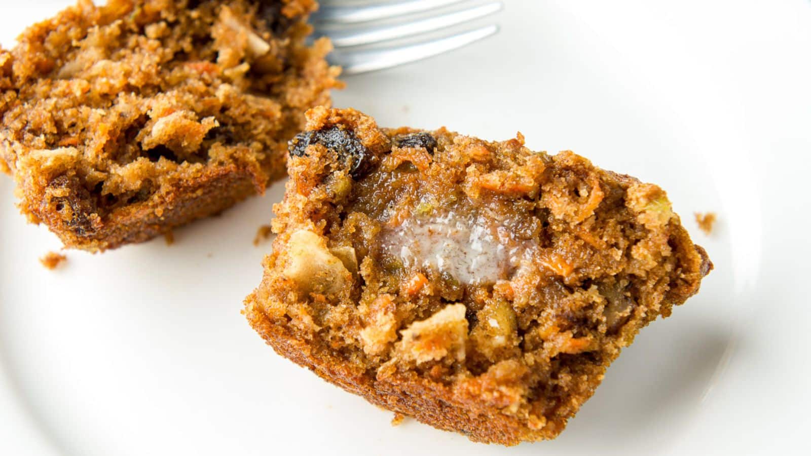 a white plate with two halves of a muffin with melted butter on one piece