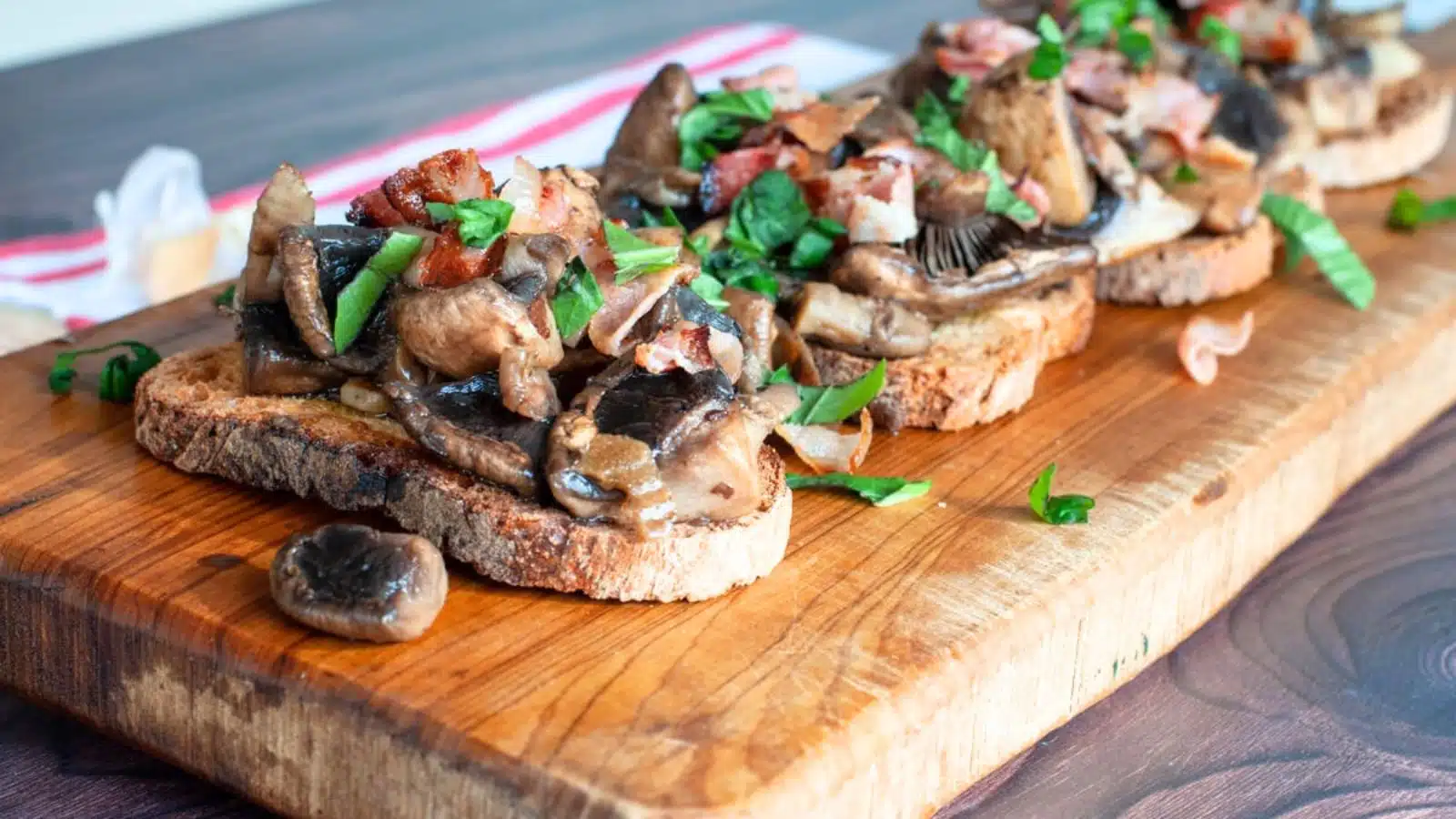 a wooden board with slices of toasted bread with sauteed mushrooms on it