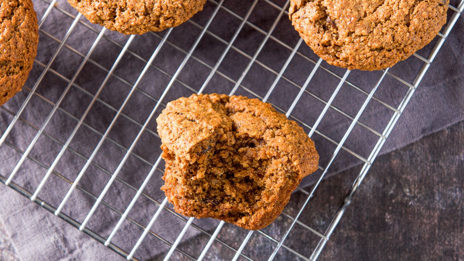 overhead view of muffins on a wire rack with a bite taken out of one of them