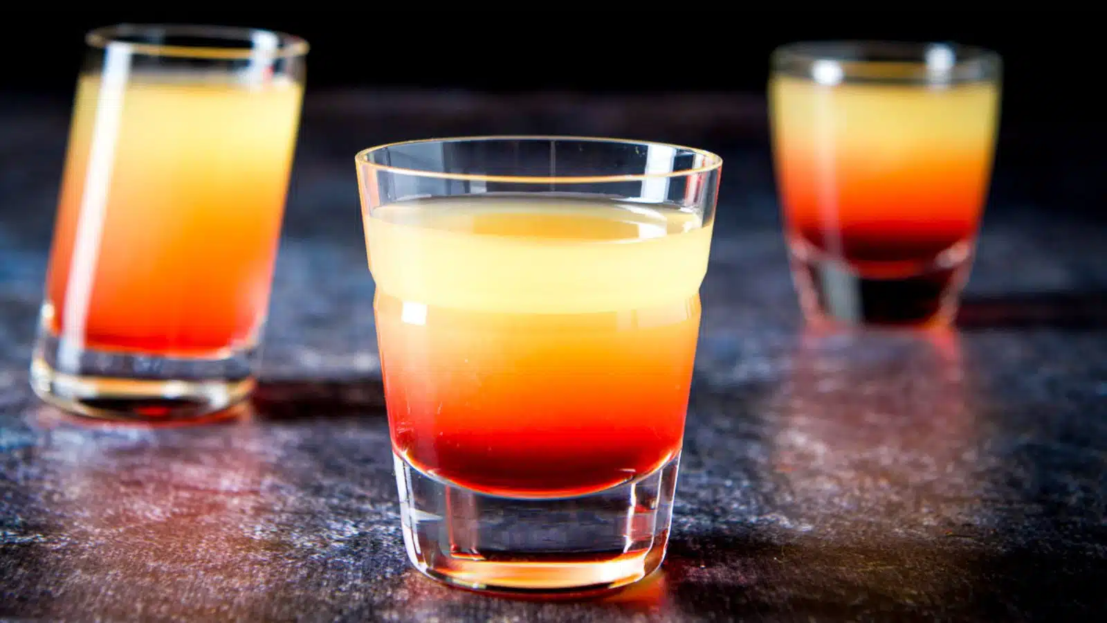 three glasses filled with the red and orange juices