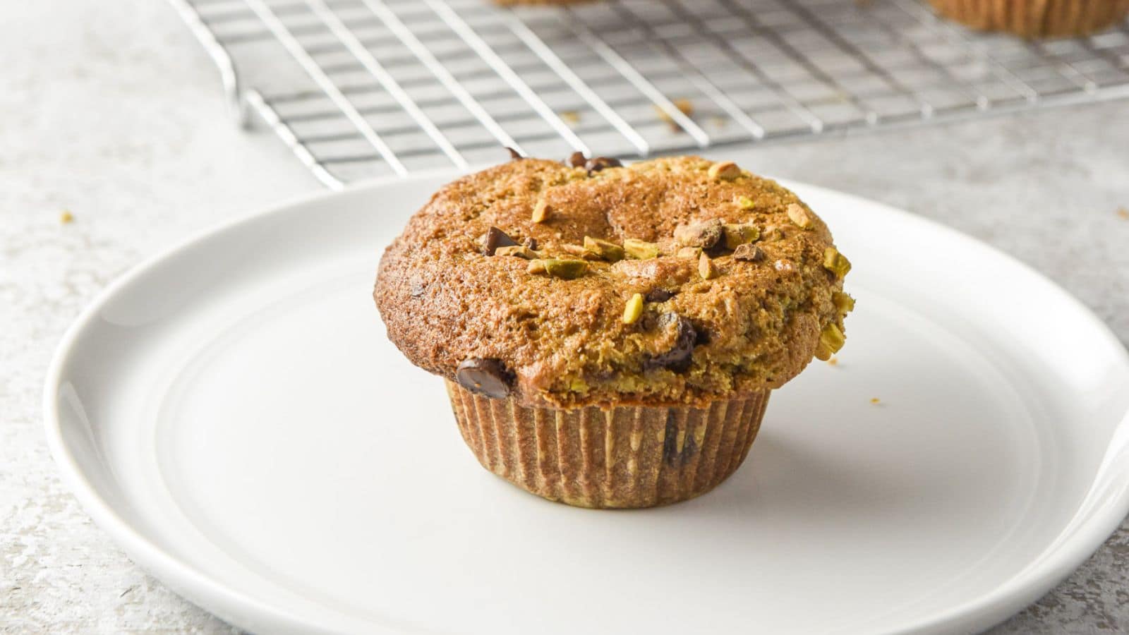 a white plate with a muffin on it and a wire rack in the back