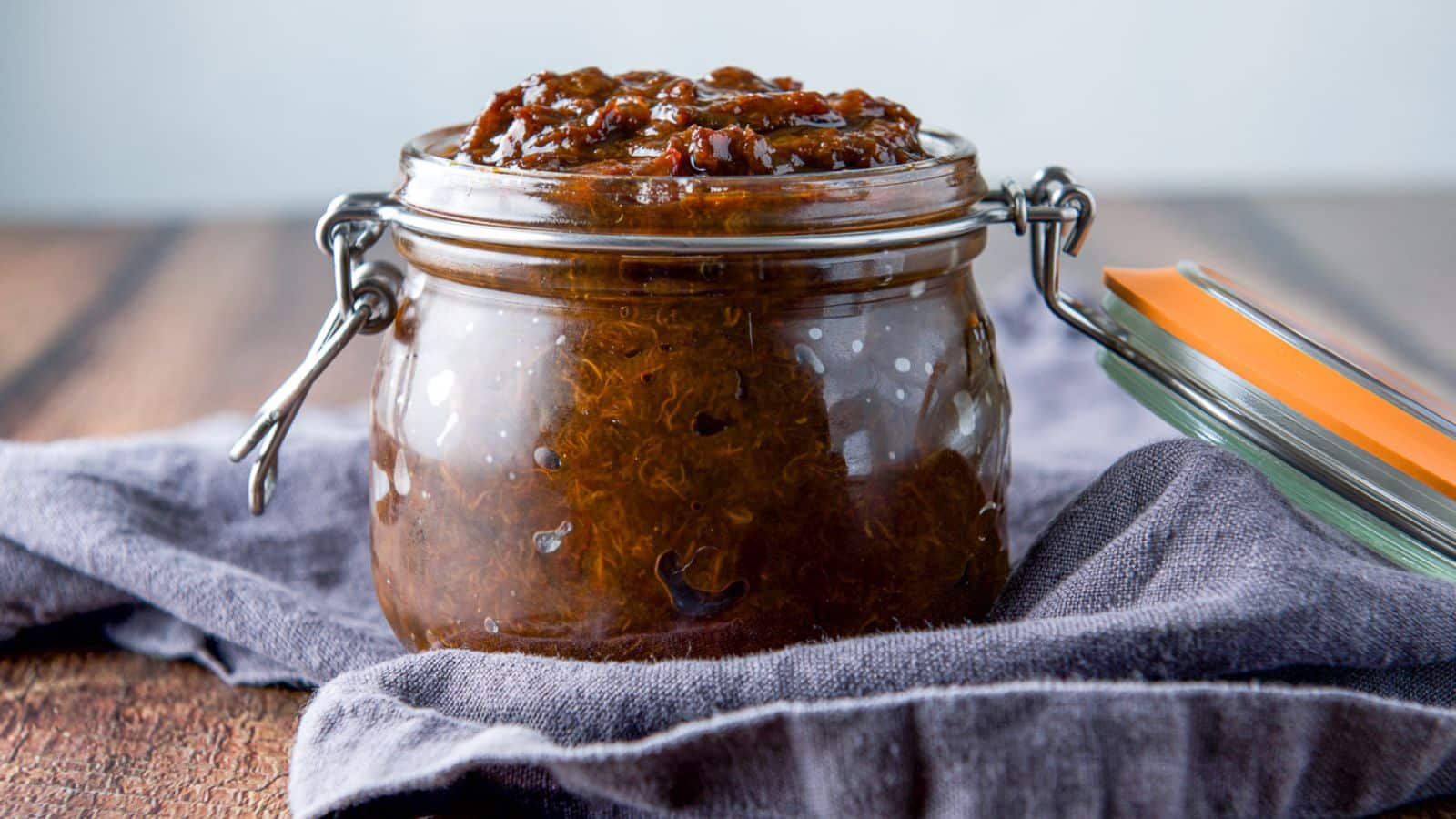 A short glass jar on a grey napkin filled with the prune spread