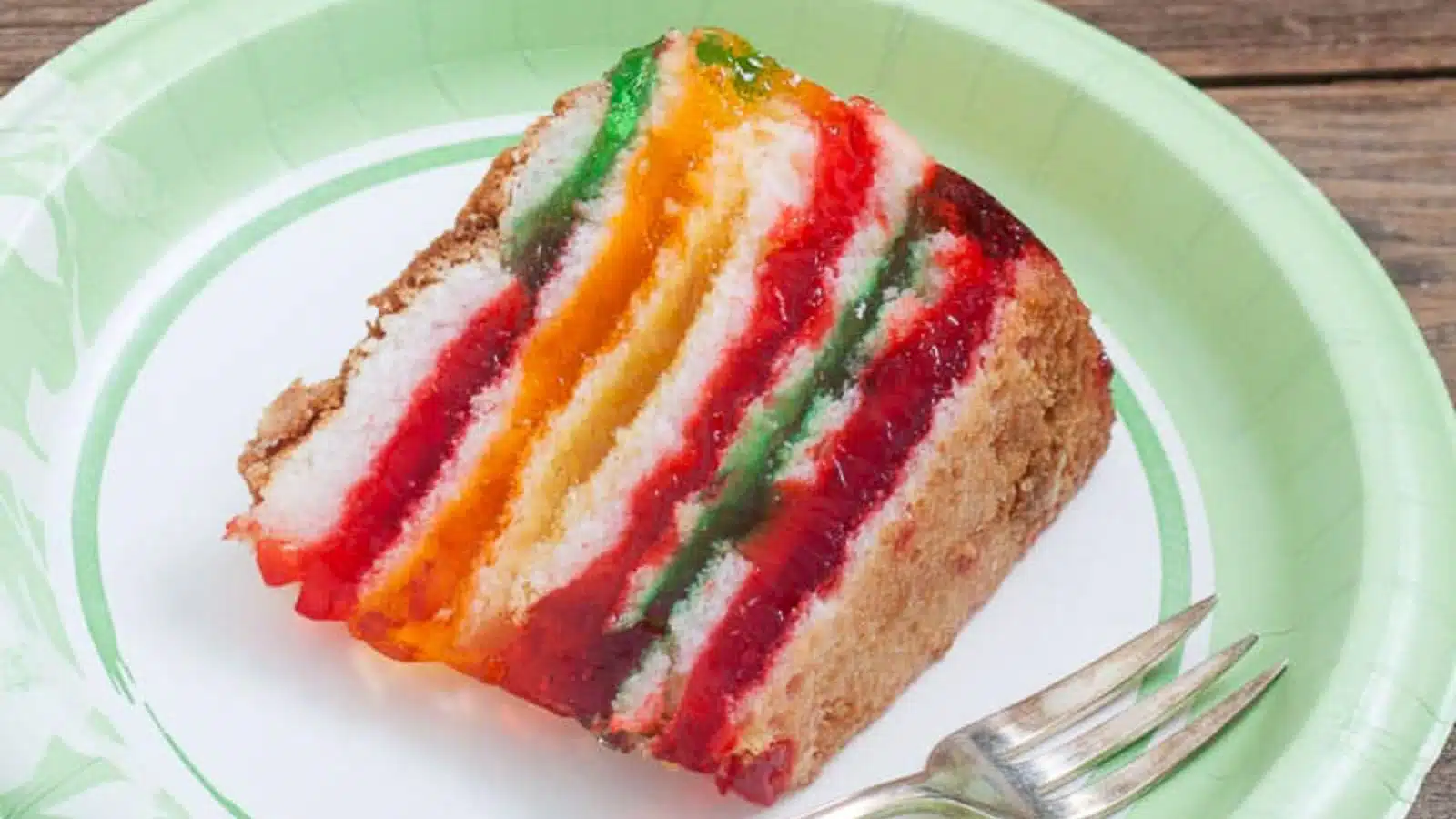 a green paper plate with a colorful piece of cake on it