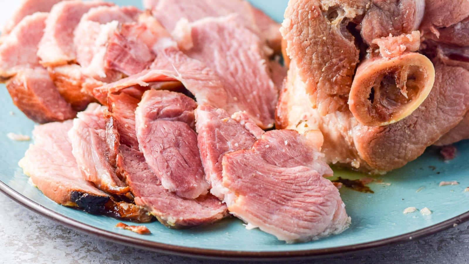 a blue platter with sliced smoked shoulder on it