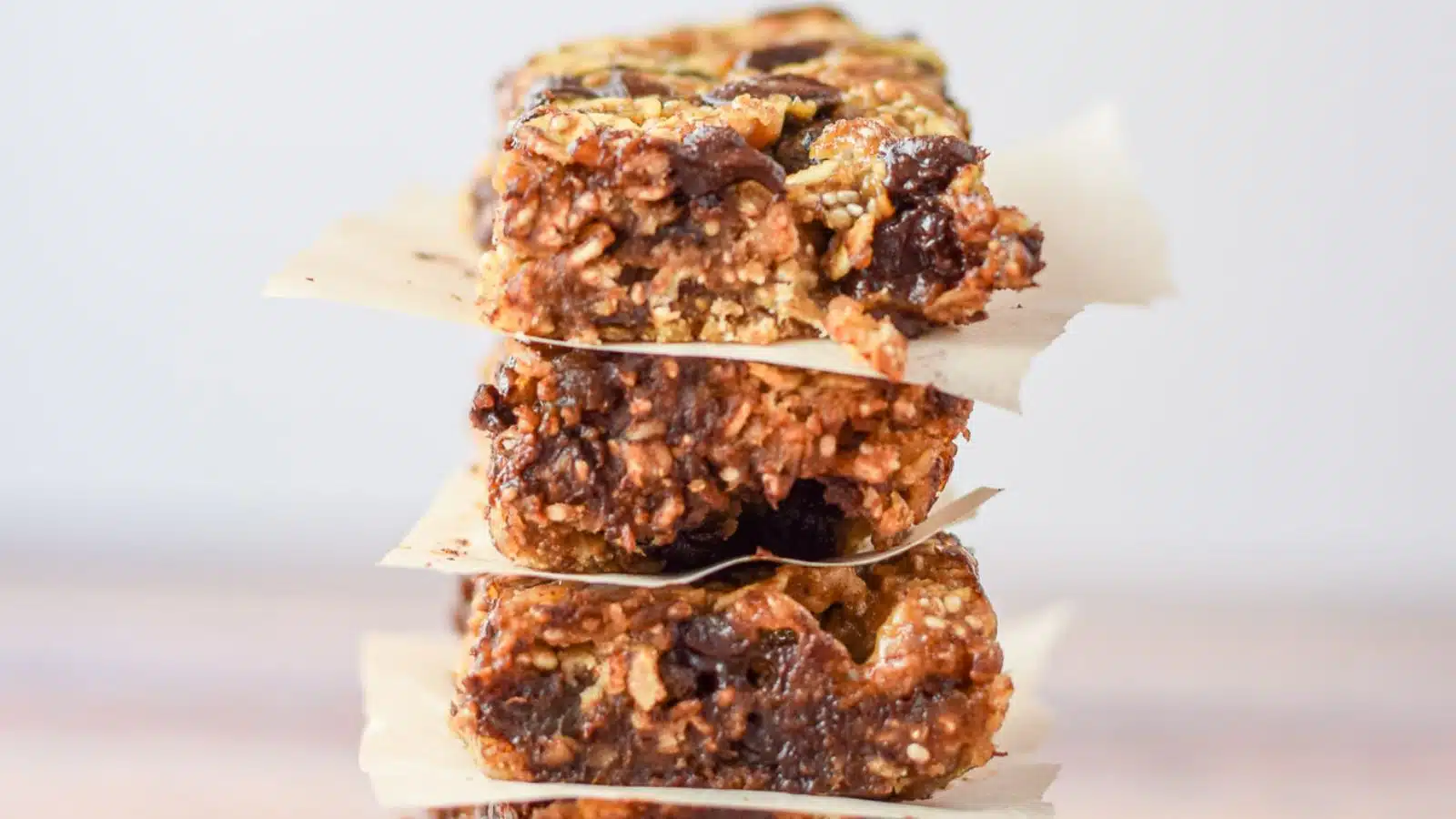 four chewy granola bars one on top of the other with parchment paper between each bar