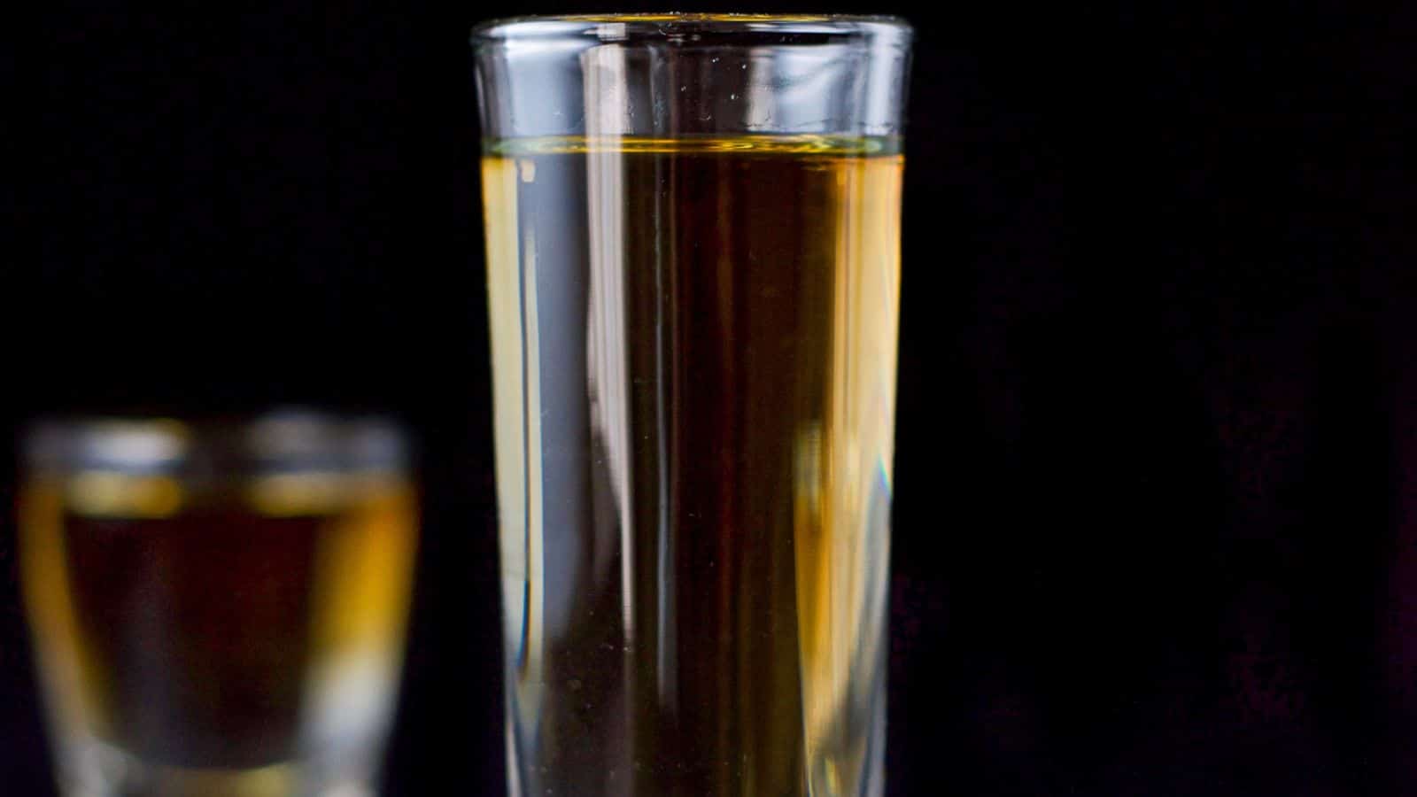 Two glasses filled with the amber liquid and a clear liquid