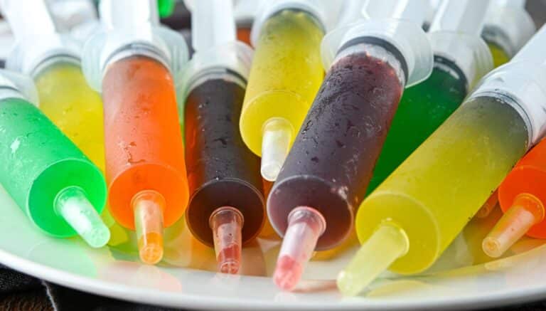 A plate with a bunch of syringes filled with jello shots