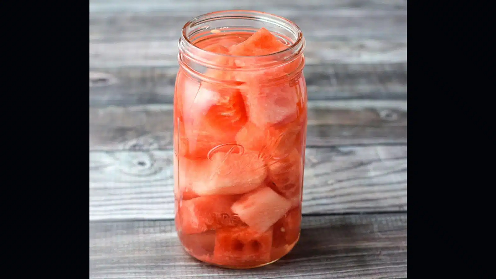 a jar with chunks of watermelon and vodka in it