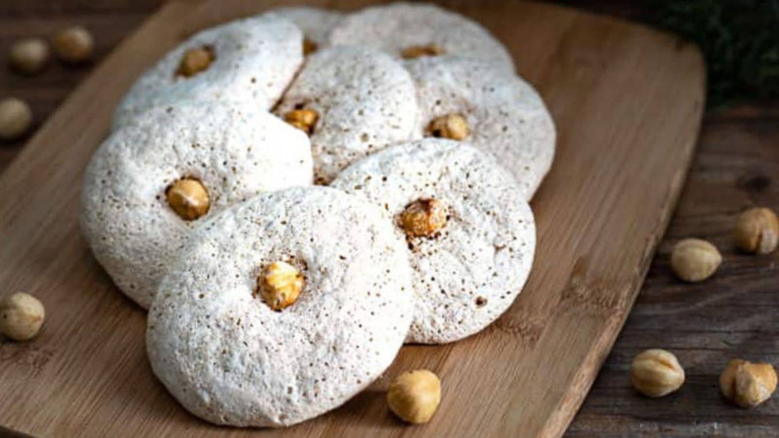 white macaroons on a board with hazelnuts