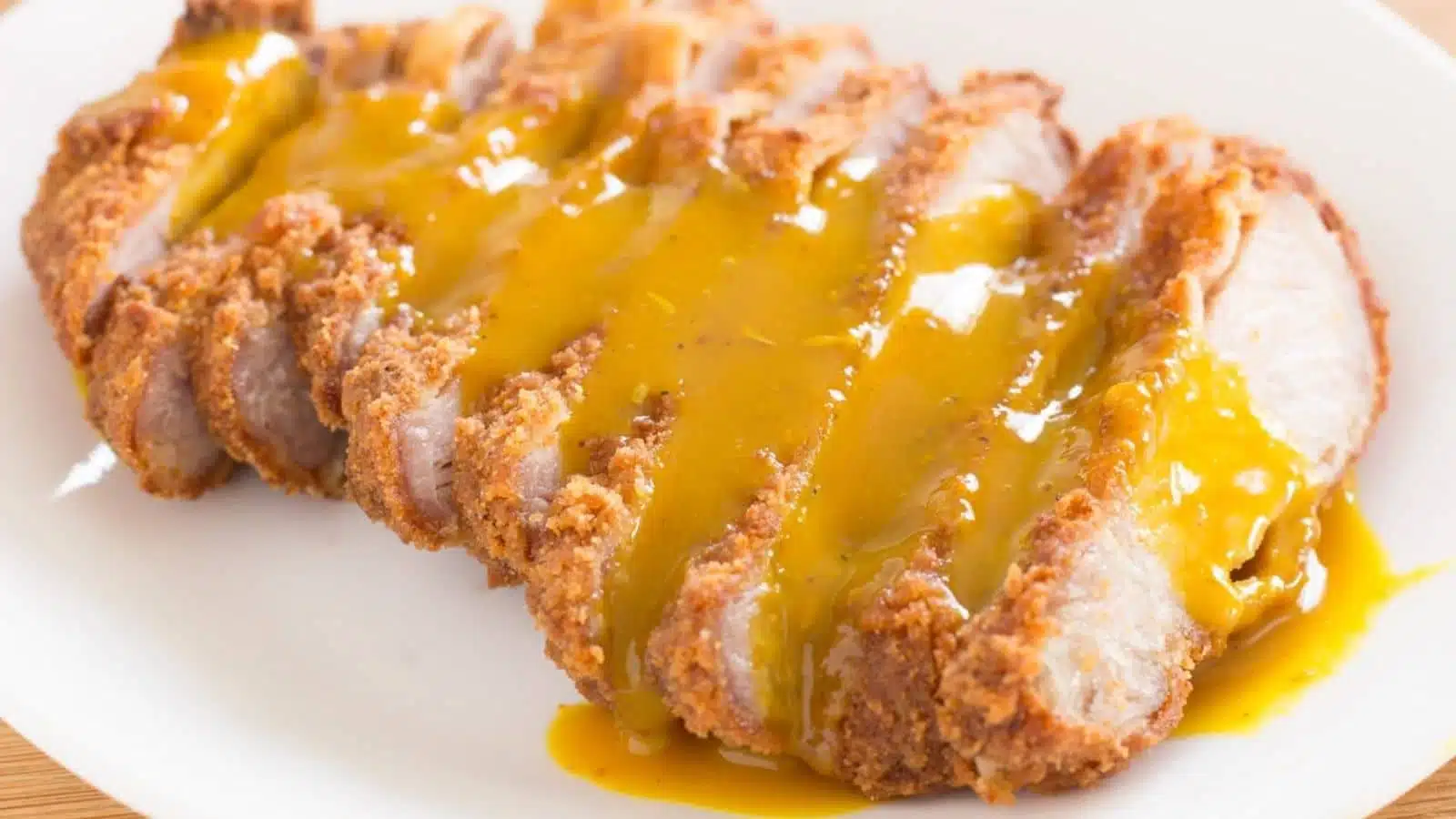 Breaded pork on a plate with a sauce on it