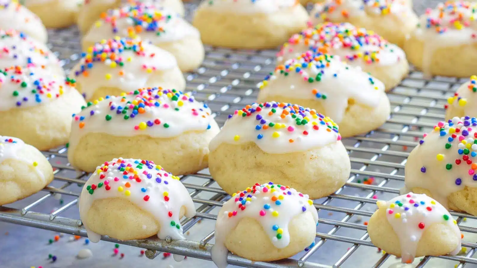Frosted ricotta cookies on a wire rack cooling